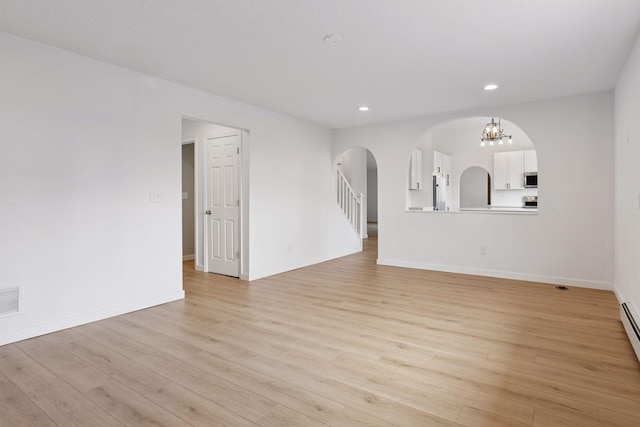 19835 County Road 30, Corcoran, MN 55340 - unfurnished living room with arched walkways, light wood-style floors, recessed lighting, a chandelier, and baseboards