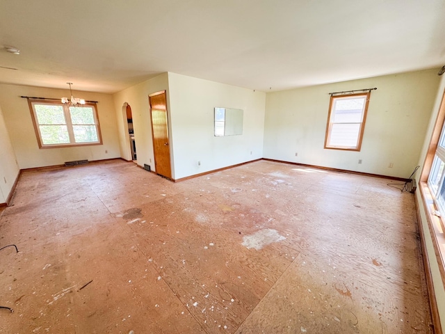 empty room with a chandelier, baseboards, arched walkways, and a smoke detector