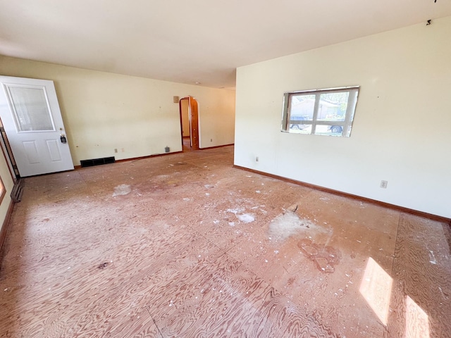 spare room featuring baseboards and arched walkways