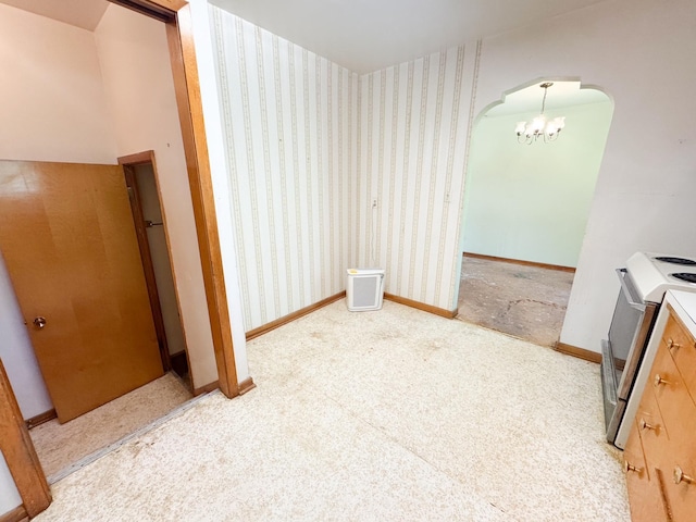 unfurnished dining area featuring arched walkways, a chandelier, carpet flooring, wallpapered walls, and baseboards