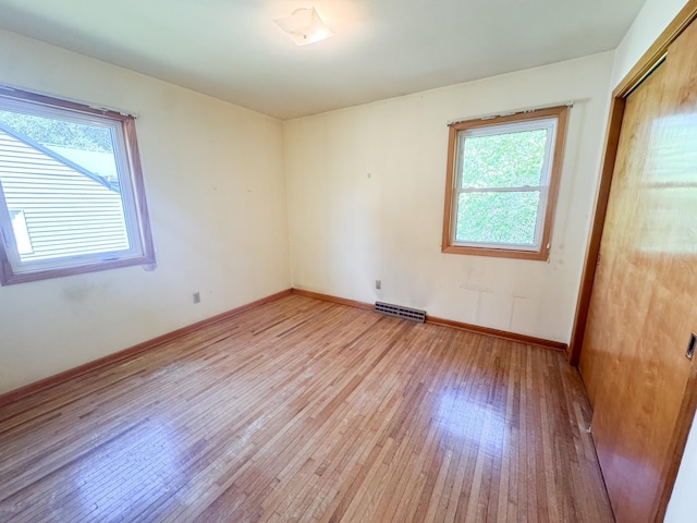 spare room with light wood-style flooring, healthy amount of natural light, and baseboards
