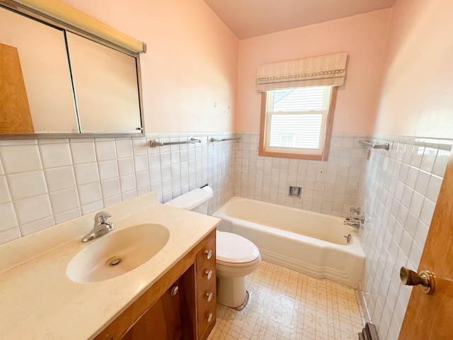 bathroom featuring tile walls, toilet, a tub, tile patterned floors, and wainscoting