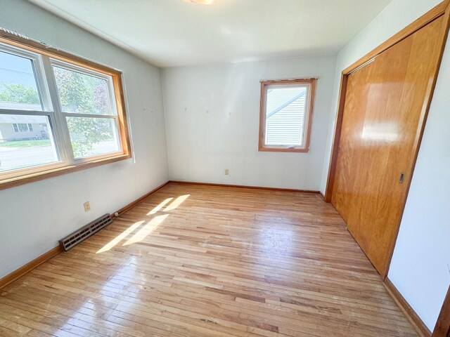 unfurnished bedroom featuring light wood-style floors, a closet, and baseboards