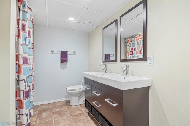 1214 8th St N, Moorhead, MN 56560 - full bathroom with a paneled ceiling, double vanity, toilet, baseboards, and tile patterned flooring