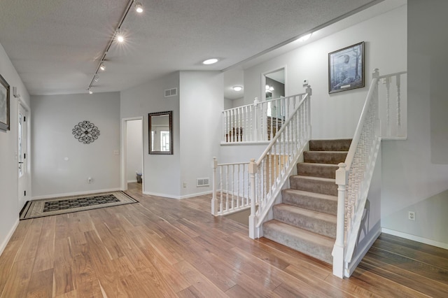 7256 Maciver Ave NE, Otsego, MN 55301 - foyer featuring rail lighting, wood finished floors, baseboards, stairway, and a textured ceiling