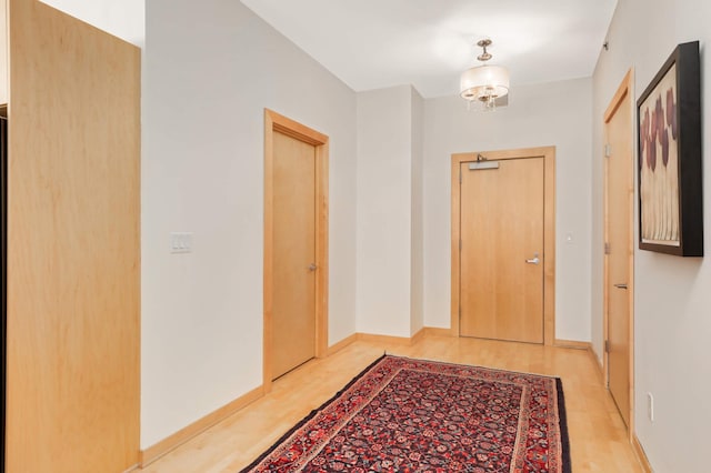 hallway featuring light wood-type flooring and baseboards