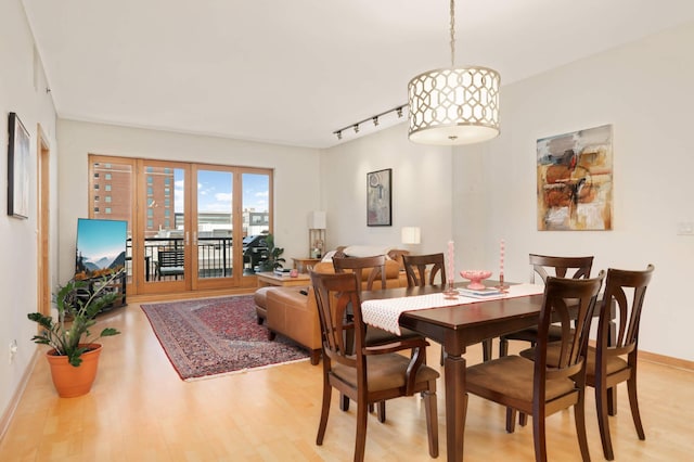 dining area with light wood-style flooring, track lighting, and baseboards