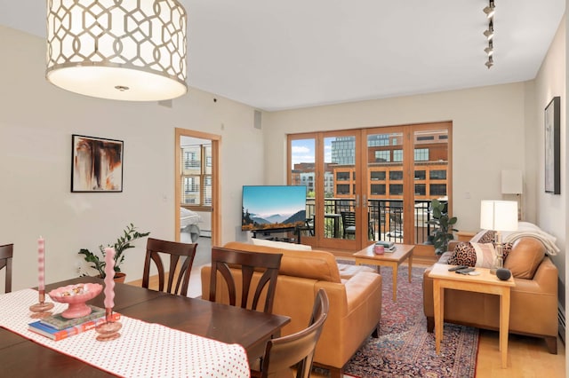 dining room with rail lighting, light wood finished floors, and baseboard heating