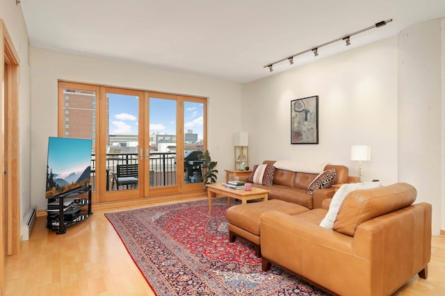 living area featuring rail lighting, light wood-style flooring, and baseboard heating