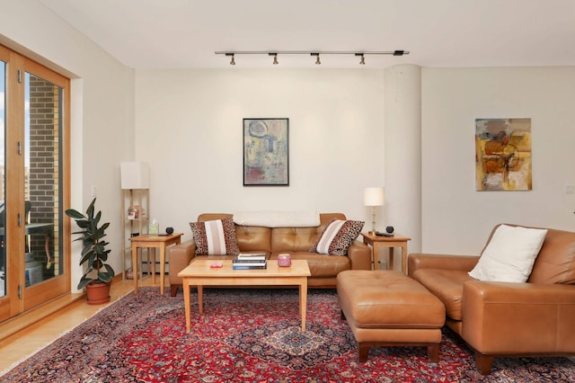 living room featuring wood finished floors, track lighting, and a baseboard radiator