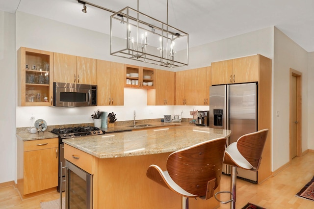 kitchen with stainless steel appliances, beverage cooler, a sink, a center island, and light stone countertops