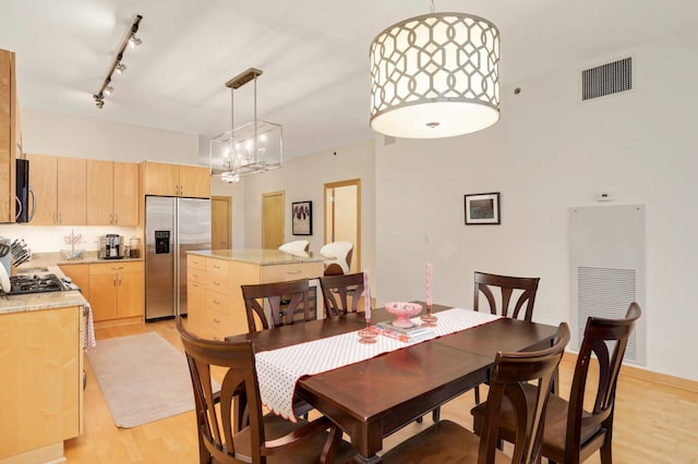 dining area featuring light wood finished floors, a chandelier, a heating unit, and track lighting