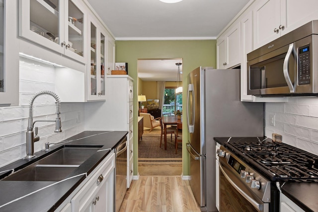 1623 Black Oaks Pl N, Plymouth, MN 55447 - kitchen with appliances with stainless steel finishes, white cabinetry, light wood-style flooring, dark countertops, and ornamental molding