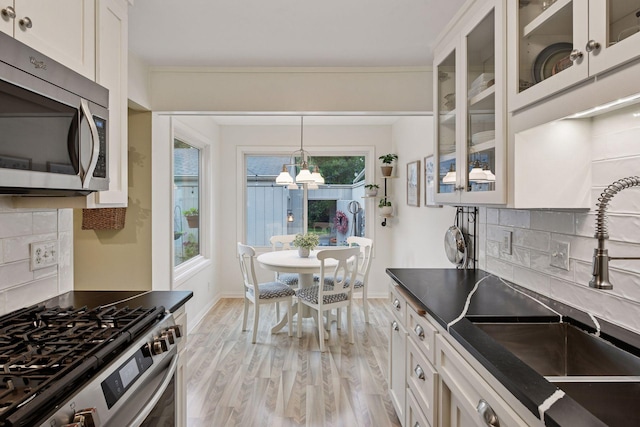1623 Black Oaks Pl N, Plymouth, MN 55447 - kitchen with stainless steel appliances, dark countertops, backsplash, light wood-style floors, and a chandelier