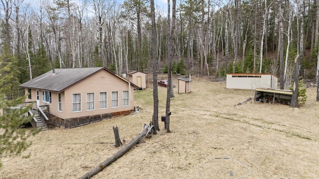 6301 Hunters Pass, Greenwood Twp, MN 55790 - view of home's exterior featuring an outdoor structure, roof with shingles, and a storage unit