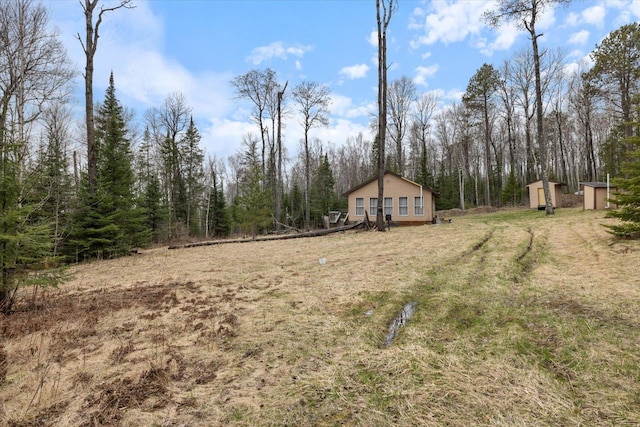 6301 Hunters Pass, Greenwood Twp, MN 55790 - view of yard featuring a storage unit, an outbuilding, and a forest view