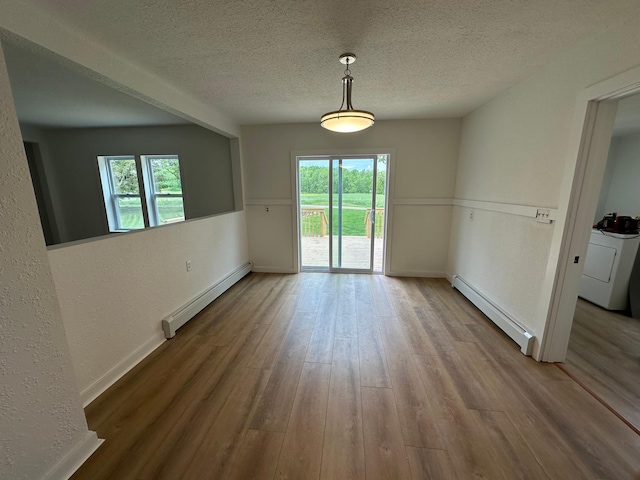 46130 Anchor Ave, Fish Lake Twp, MN 55080 - unfurnished dining area featuring a baseboard heating unit, washer / clothes dryer, wood finished floors, baseboards, and a textured ceiling