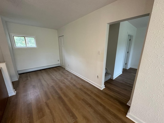 46130 Anchor Ave, Fish Lake Twp, MN 55080 - unfurnished room featuring a baseboard heating unit, dark wood-type flooring, baseboards, and stairs