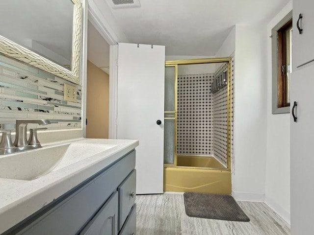 213 1st Ave E, Truman, MN 56088 - full bathroom with backsplash, shower / bath combination with glass door, wood finished floors, and vanity