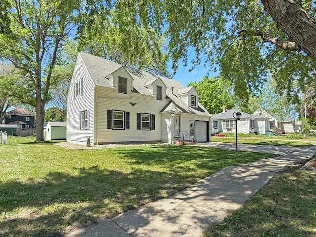 213 1st Ave E, Truman, MN 56088 - cape cod house featuring concrete driveway, a front yard, a shingled roof, and a shed