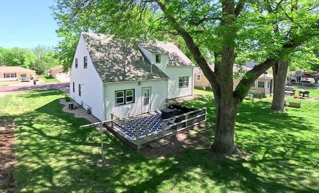 213 1st Ave E, Truman, MN 56088 - back of property featuring a lawn, a shingled roof, cooling unit, and a wooden deck