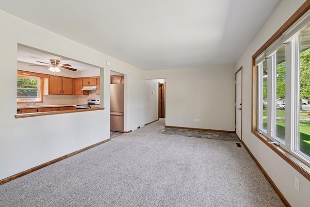 unfurnished living room featuring plenty of natural light, light carpet, and baseboards