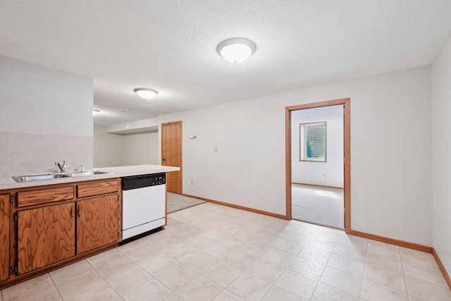 kitchen with a sink, white dishwasher, light countertops, baseboards, and a textured ceiling