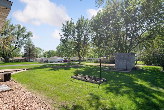 view of grassy yard featuring a storage unit and central AC unit