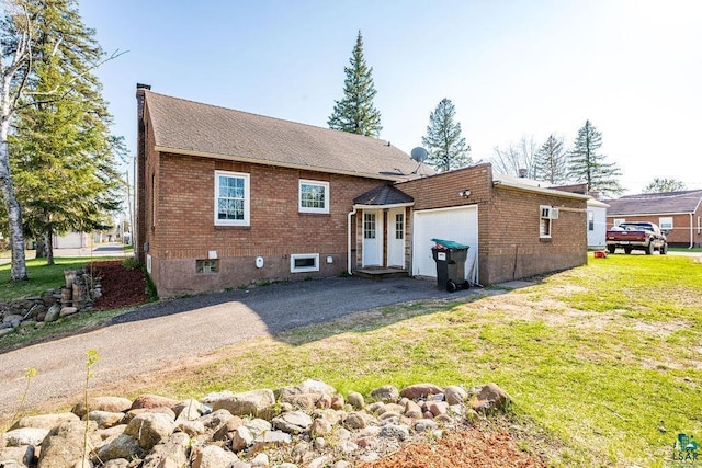 1815 Carlton Ave, Cloquet, MN 55720 - rear view of house featuring an attached garage, brick siding, asphalt driveway, and a yard