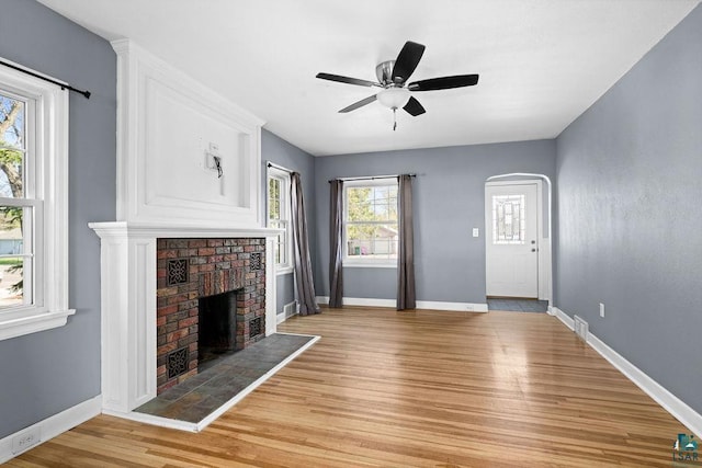 1815 Carlton Ave, Cloquet, MN 55720 - unfurnished living room with light wood-style flooring, ceiling fan, a brick fireplace, and baseboards