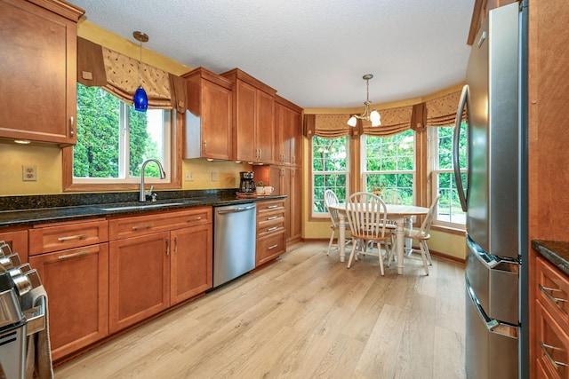 2917 85th St E, Inver Grove Heights, MN 55076 - kitchen featuring stainless steel appliances, a sink, brown cabinetry, light wood-type flooring, and a textured ceiling