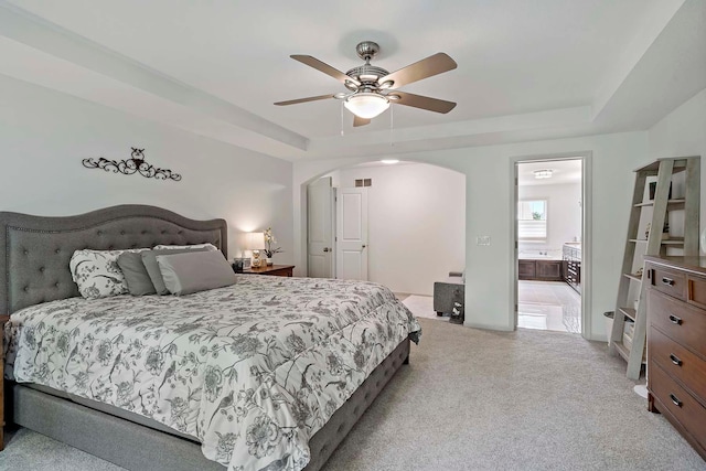 5315 Ranchview Ln N, Plymouth, MN 55446 - bedroom featuring a tray ceiling, arched walkways, light colored carpet, ceiling fan, and ensuite bath