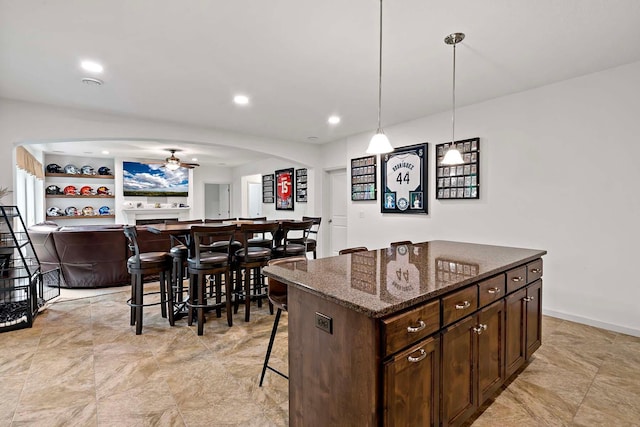 5315 Ranchview Ln N, Plymouth, MN 55446 - kitchen with arched walkways, a kitchen bar, a ceiling fan, dark brown cabinets, and dark stone countertops