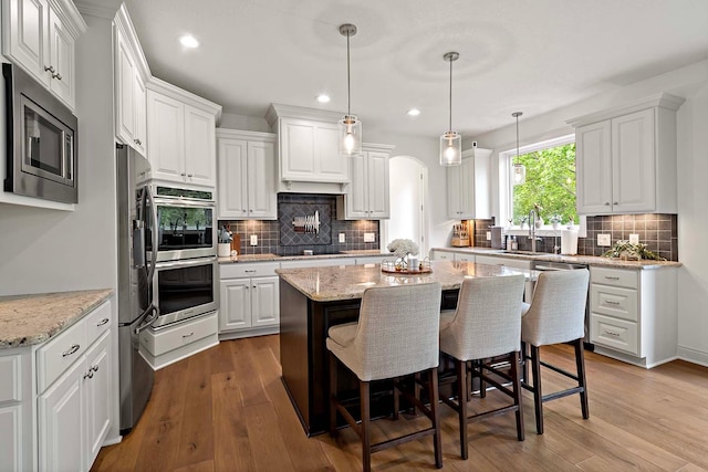 5315 Ranchview Ln N, Plymouth, MN 55446 - kitchen featuring appliances with stainless steel finishes, a kitchen island, white cabinets, backsplash, and recessed lighting