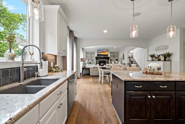 5315 Ranchview Ln N, Plymouth, MN 55446 - kitchen featuring a sink, arched walkways, white cabinetry, a fireplace, and backsplash