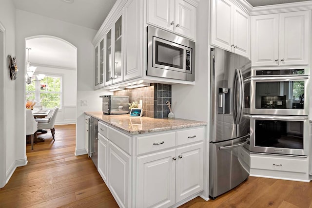 5315 Ranchview Ln N, Plymouth, MN 55446 - kitchen with appliances with stainless steel finishes, arched walkways, light wood-type flooring, white cabinetry, and glass insert cabinets
