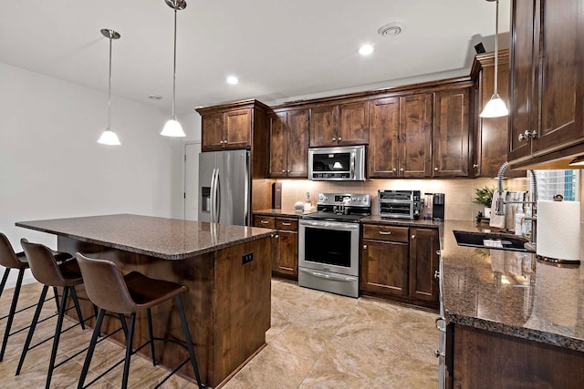 5315 Ranchview Ln N, Plymouth, MN 55446 - kitchen with appliances with stainless steel finishes, dark brown cabinets, a center island, a breakfast bar area, and dark stone counters