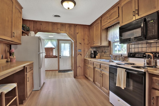 1379 7th Ave SE, Forest Lake, MN 55025 - kitchen with electric range oven, black microwave, freestanding refrigerator, light countertops, and light wood-type flooring