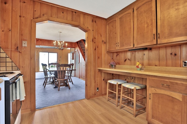 1379 7th Ave SE, Forest Lake, MN 55025 - kitchen featuring wood walls, electric stove, a chandelier, light wood-style flooring, and brown cabinets