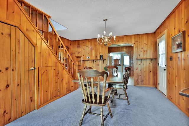 1379 7th Ave SE, Forest Lake, MN 55025 - dining space featuring stairway, wood walls, carpet floors, a chandelier, and a textured ceiling
