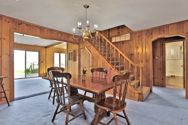 1379 7th Ave SE, Forest Lake, MN 55025 - dining room featuring wood walls, carpet, a chandelier, arched walkways, and stairs