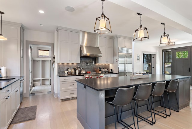 5808 Oaklawn Ave, Edina, MN 55424 - kitchen with appliances with stainless steel finishes, dark countertops, wall chimney range hood, light wood-style flooring, and backsplash