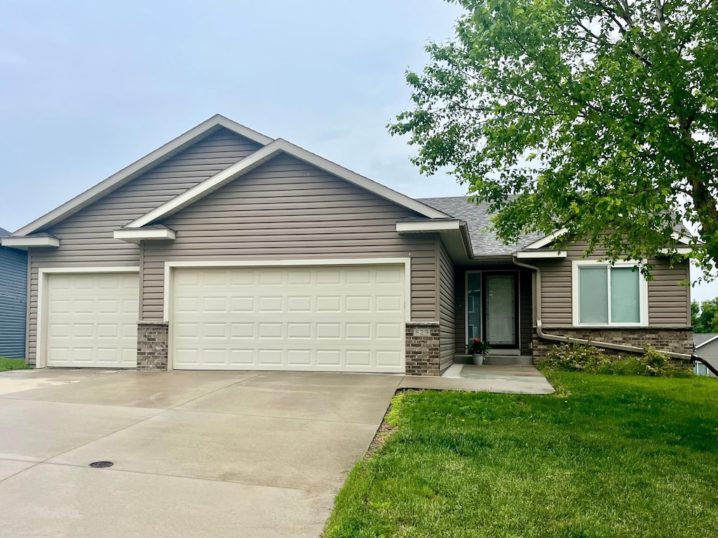 829 Dubuque Blvd, Zumbrota, MN 55992 - view of front facade with concrete driveway, an attached garage, a front yard, and brick siding