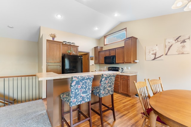 829 Dubuque Blvd, Zumbrota, MN 55992 - kitchen featuring black appliances, light countertops, a kitchen bar, light wood-type flooring, and a kitchen island
