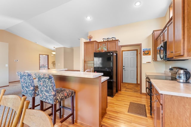 829 Dubuque Blvd, Zumbrota, MN 55992 - kitchen with black appliances, a breakfast bar area, brown cabinets, light countertops, and light wood-style flooring