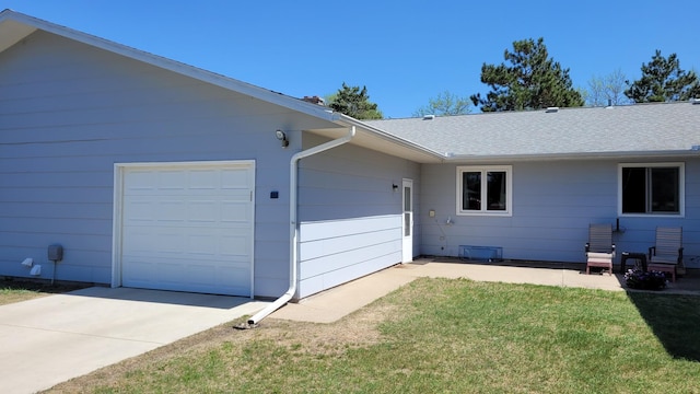 view of property exterior featuring an attached garage, a yard, concrete driveway, and roof with shingles