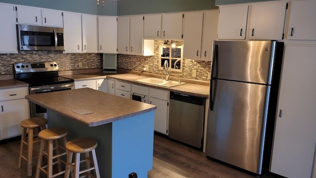 kitchen with appliances with stainless steel finishes, a sink, white cabinetry, and dark wood-style flooring