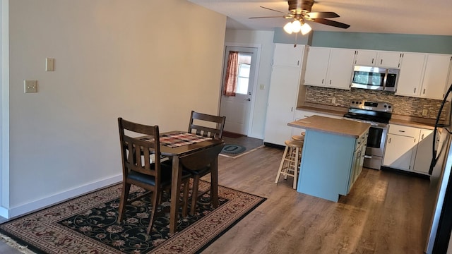 kitchen featuring stainless steel appliances, backsplash, white cabinets, and a kitchen bar