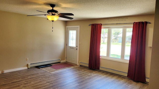spare room featuring a baseboard radiator, healthy amount of natural light, wood finished floors, and a textured ceiling