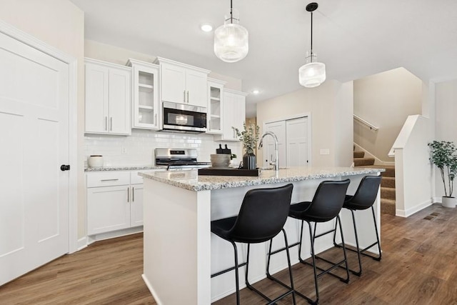 kitchen with appliances with stainless steel finishes, a sink, dark wood-style flooring, tasteful backsplash, and recessed lighting